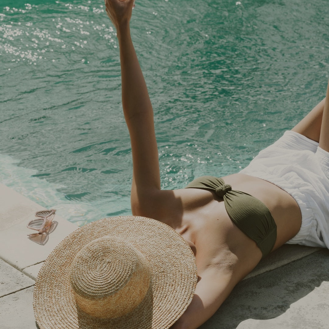 Woman by the pool with sleek, shiny hair protected by heat protectant spray – summer haircare with Antidote